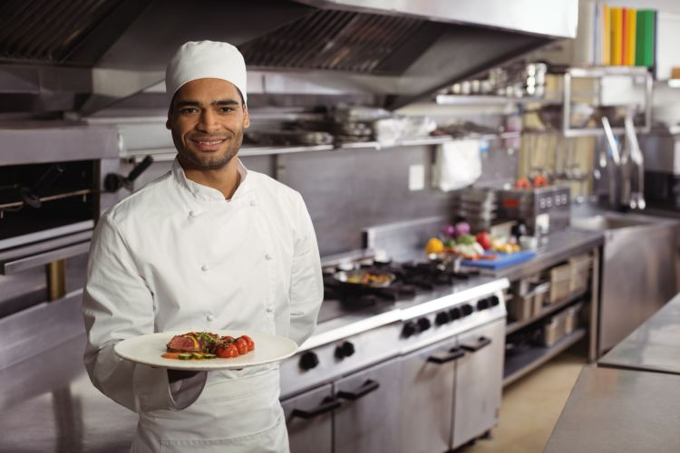 Portrait of smiling chef holding delicious dish in kitchen